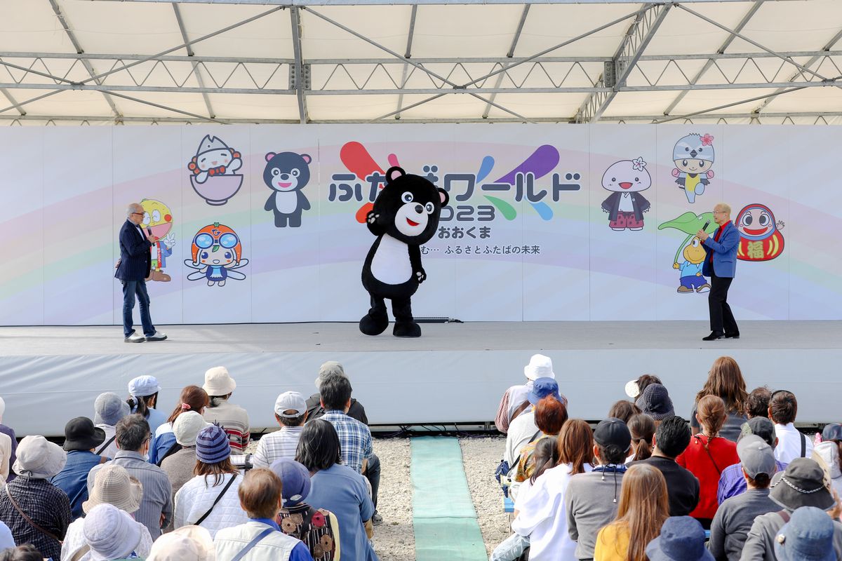 町公式キャラクター・まあちゃんとレジェンド声優の神谷明さん（右）、中尾隆聖さん（左）のステージを観覧する来場者ら
