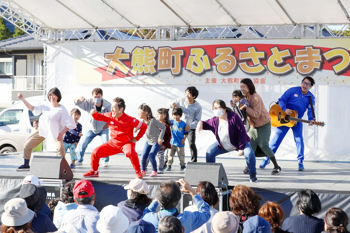 大熊町ふるさとまつりが10月21日、学び舎ゆめの森近くの特設会場で開催されました。当日は約1,600人が来場し、ステージイベントや30を超える出店を楽しみました。お笑い芸人のショーでは、来場者らが有名芸人のテツandトモさんと一緒にパフォーマンスを披露し、会場に笑いを巻き起こしました。