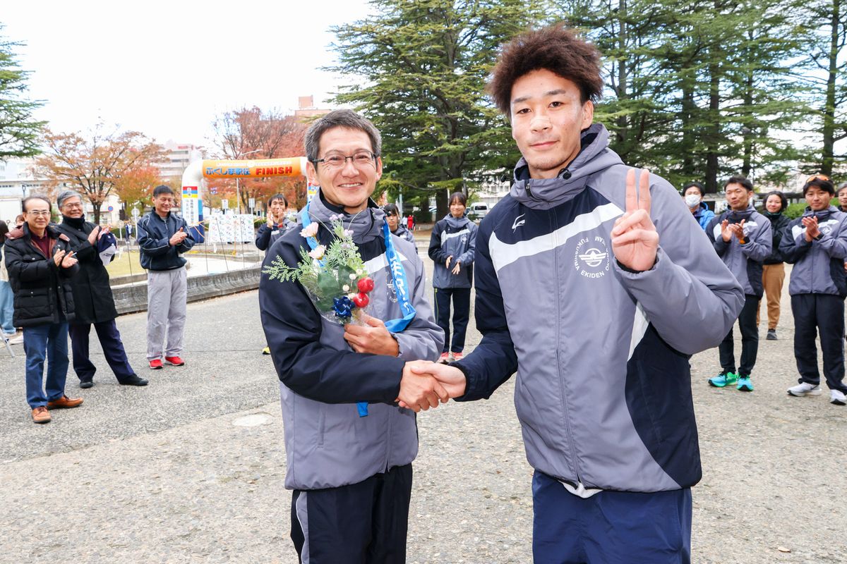吉田充芳コーチと柳田主将から記念品と花束が渡辺監督へ手渡され、渡辺監督は満面の笑みを見せました。写真は花束を受け取る渡辺監督（左）。