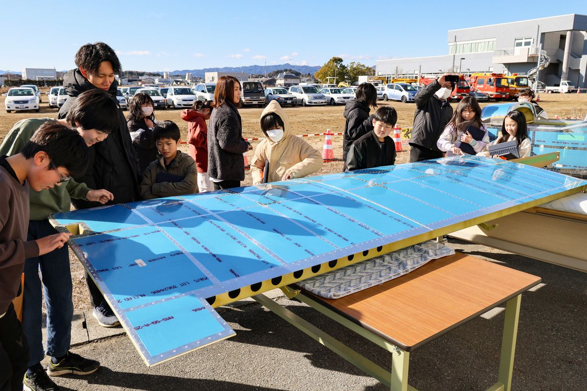 学生が制作中の飛行機を間近で見学する子どもたち