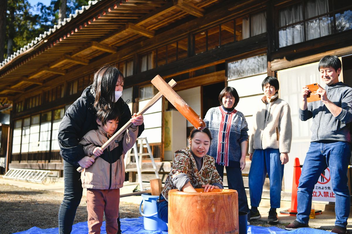 渡部家住宅で一緒に杵を持って餅をつく親子（左）