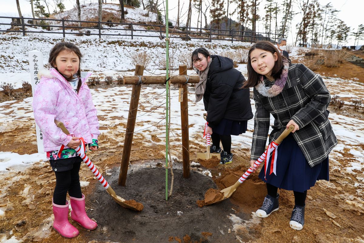 きぼうの桜に土をかける卒園児と卒業生ら3人