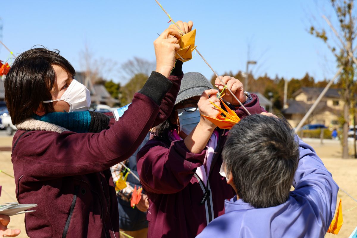 張られたロープに折り鶴を飾る参加者