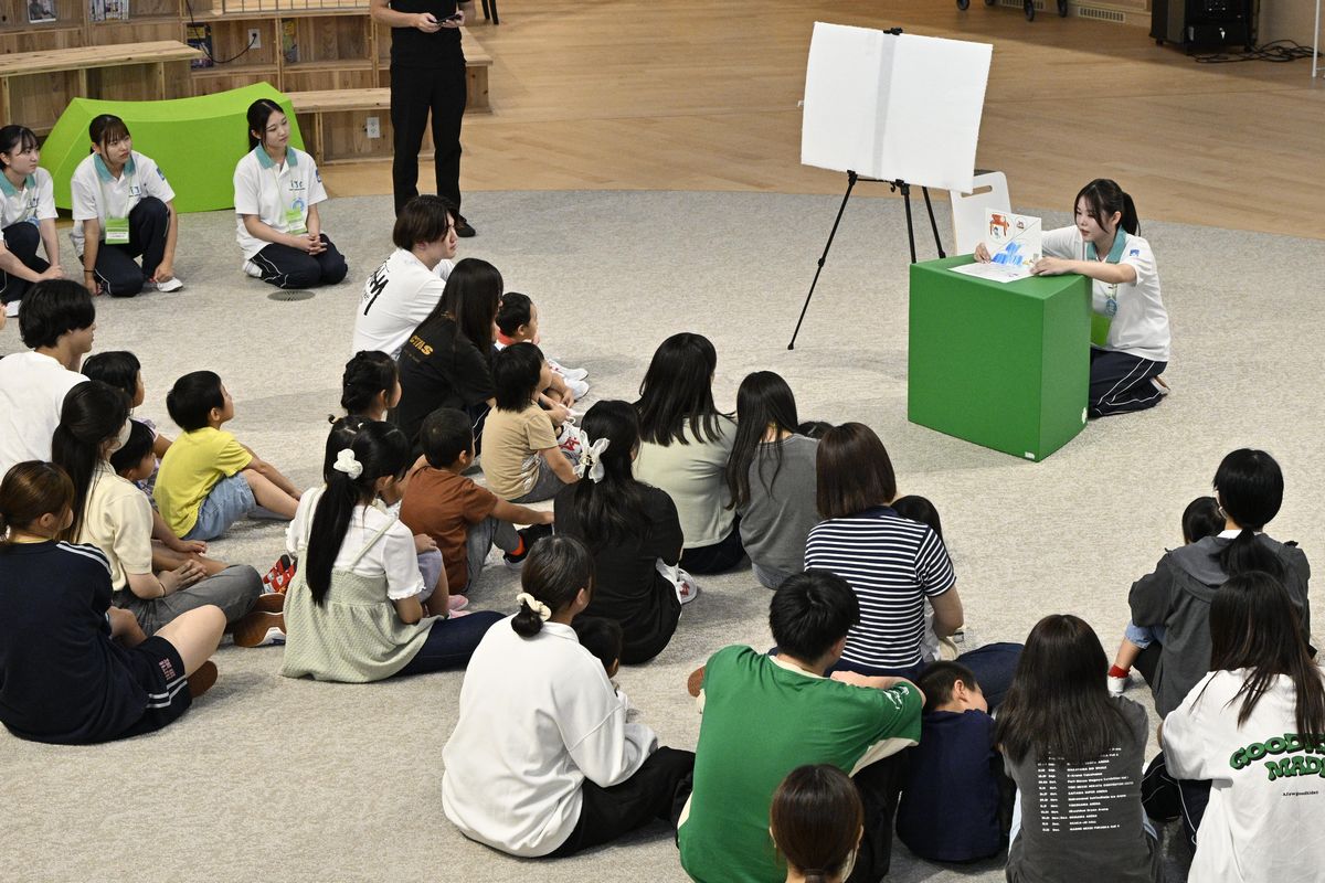 園児たちに紙芝居を読み聞かせする学生