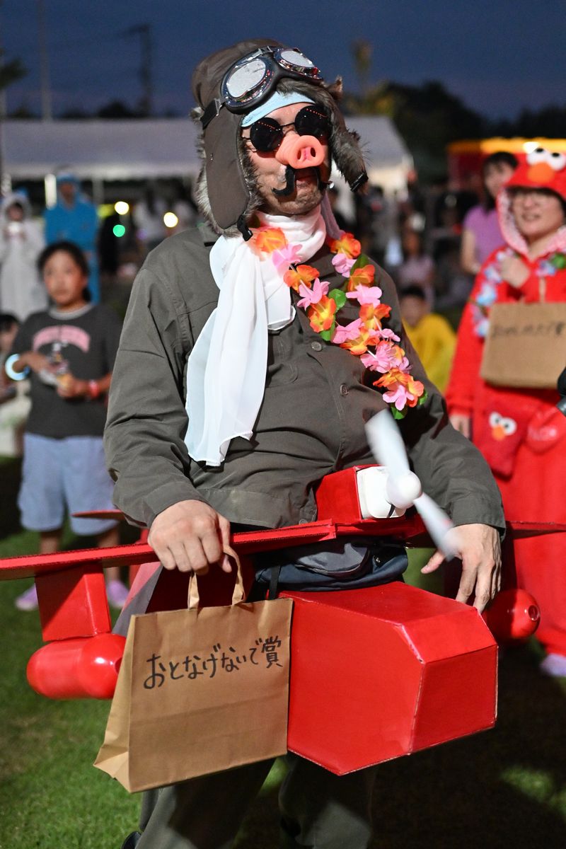 盆踊り表彰式で「おとなげないで賞」を受賞し、レイを首にかけれられた参加者。有名なアニメのキャラクターに扮し会場を盛り上げました。
