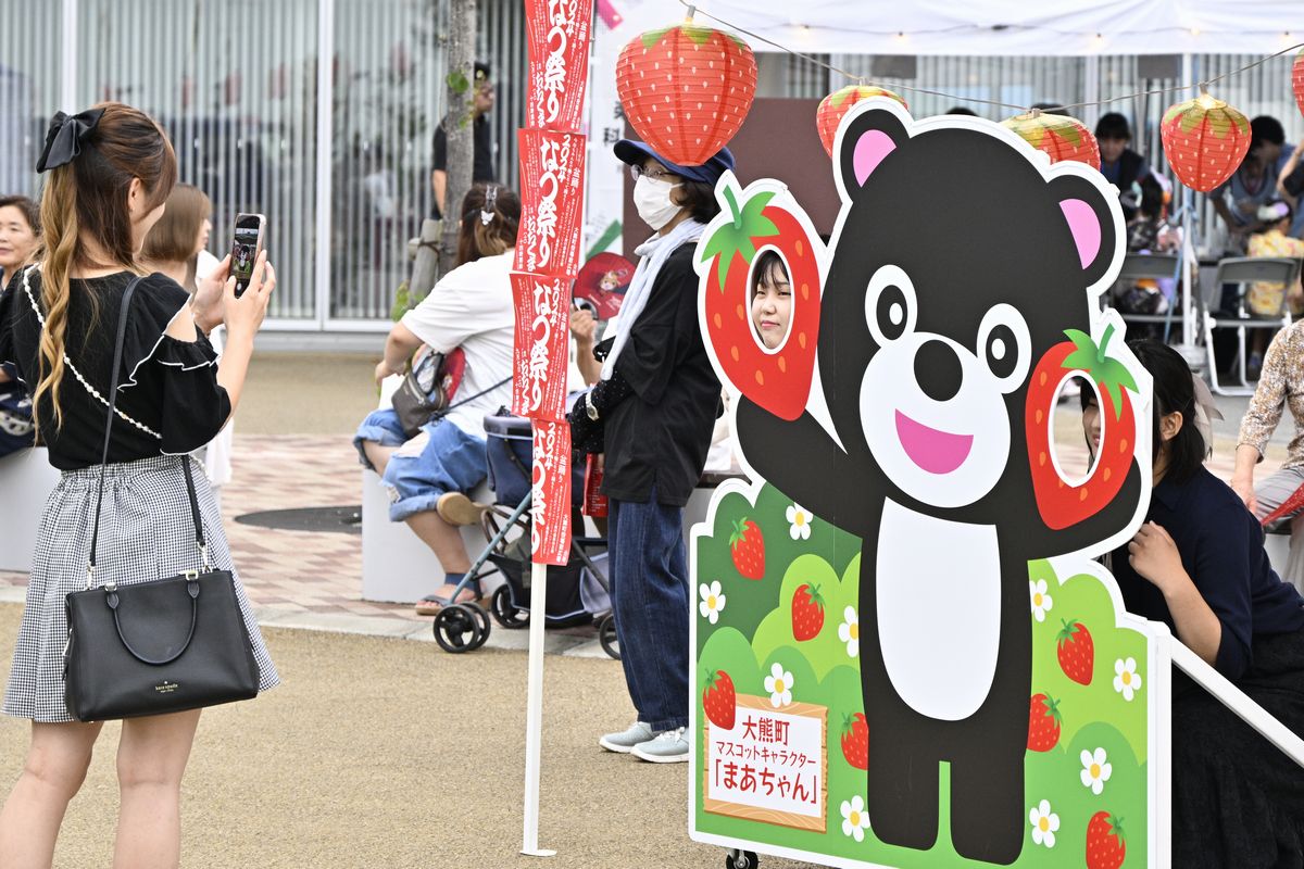 町のマスコットキャラクター「まあちゃん」の顔はめパネルで写真を撮る来場者。