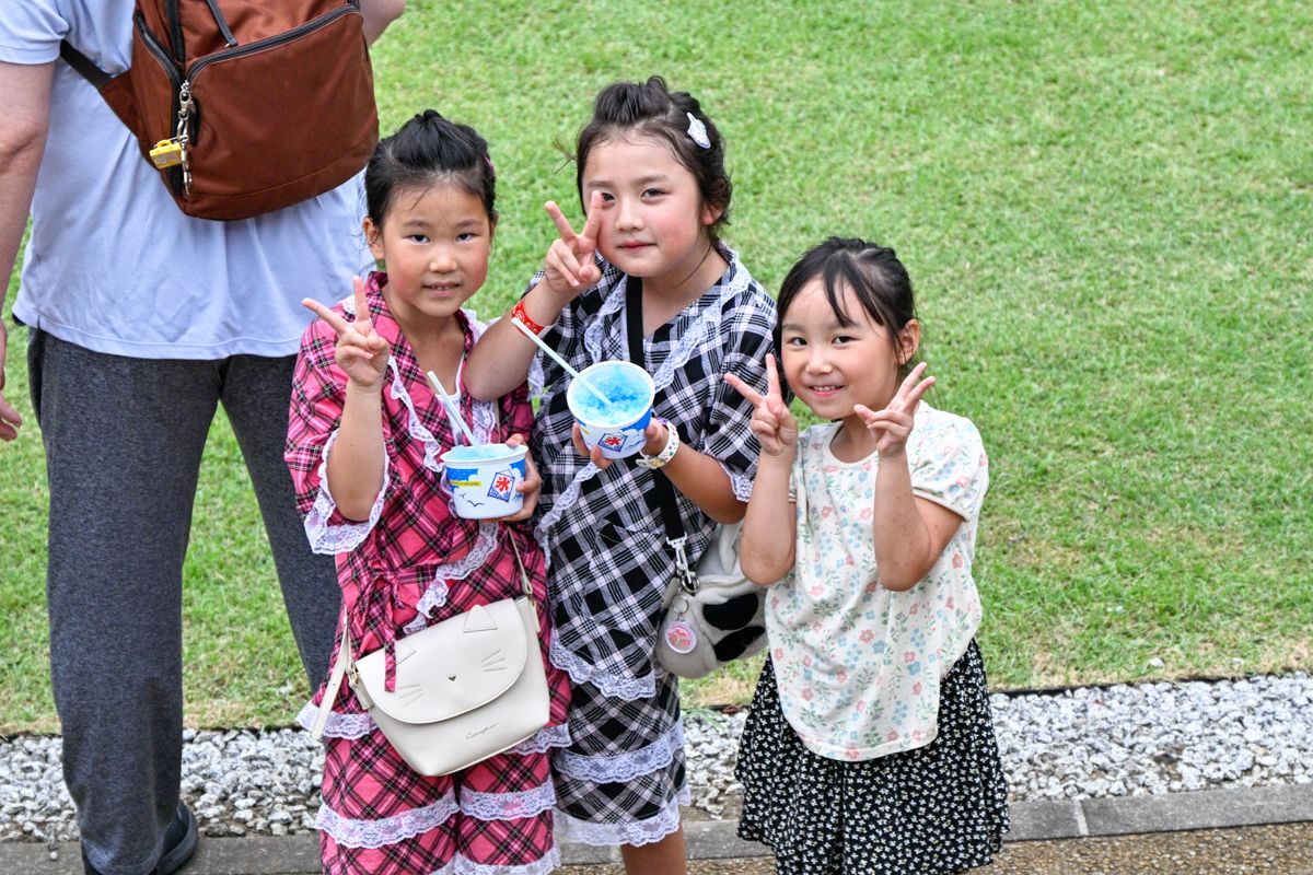 夏の風物詩かき氷。カラフルなシロップがかかったかき氷を手に持ち、祭りを楽しむ子どもたち。