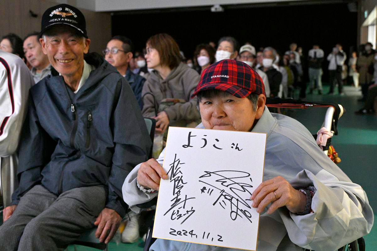 お笑いコンビぺこぱの松陰寺太勇（しょういんじたいゆう）さんのサインを嬉しそうに見せる来場者。