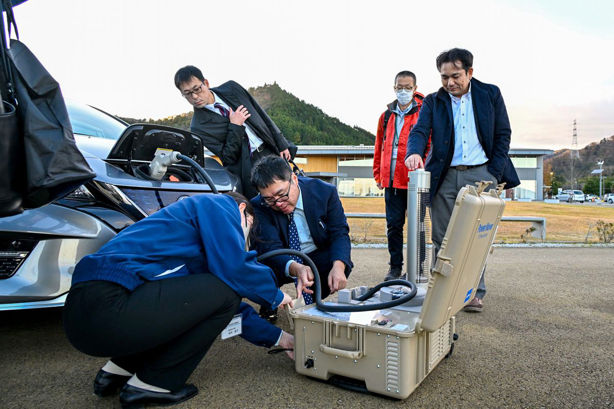 電気自動車からの給電を体験する参加者ら