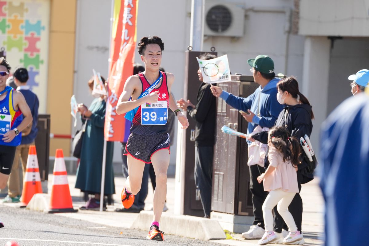 ふくしま駅伝の最長区間である第10区（平成記念郡山こどものもり公園入口前から本宮市・白岩屋商店前）10.6kmを走る柳田（明）選手。沿道には多くの人々が集まり、応援の手旗を振りながら選手たちを力強く応援する姿が見られました。