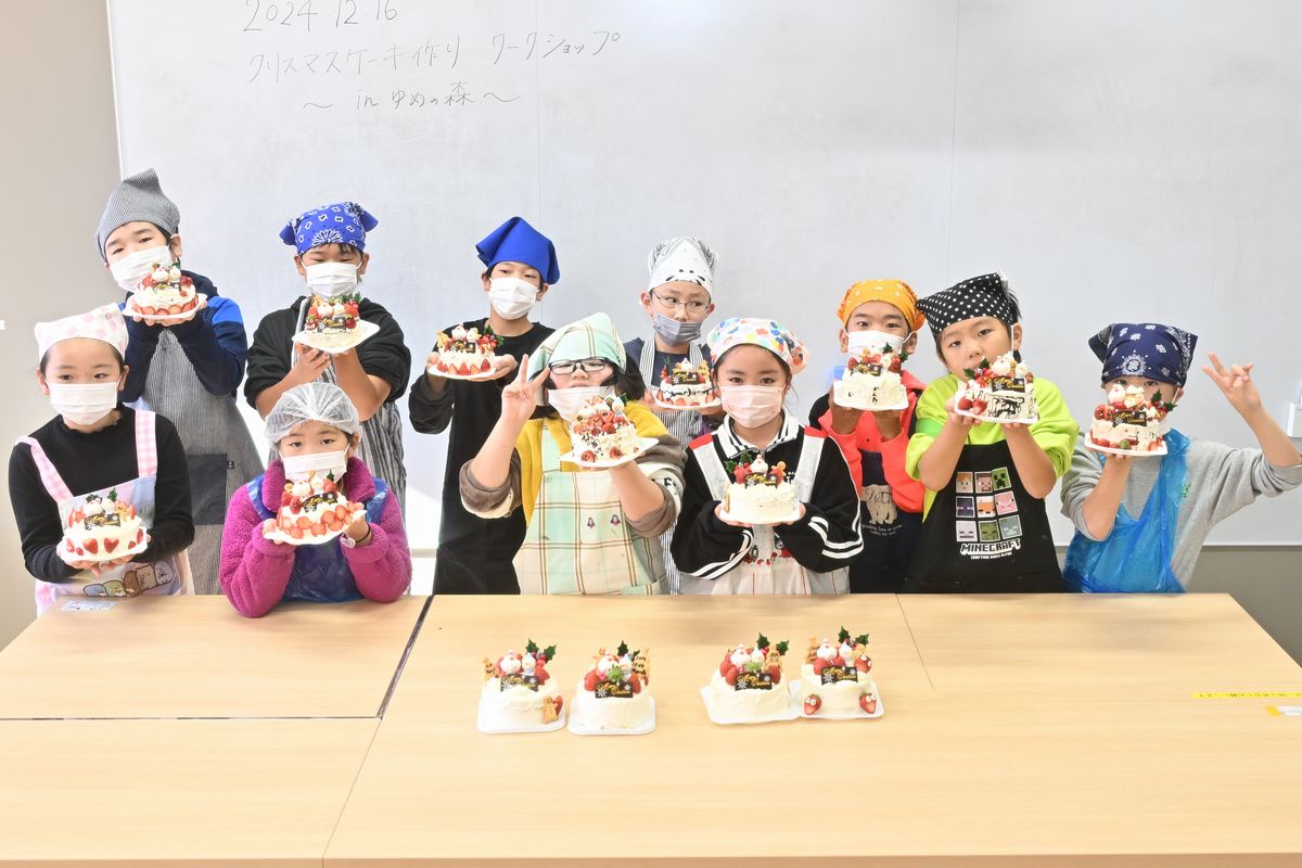 出来上がったクリスマスケーキを見せる子どもたち
