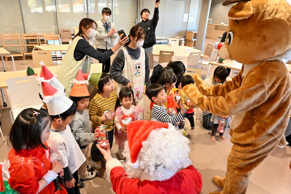 サンタさんから長ぐつに入ったプレゼントをもらう子どもたち