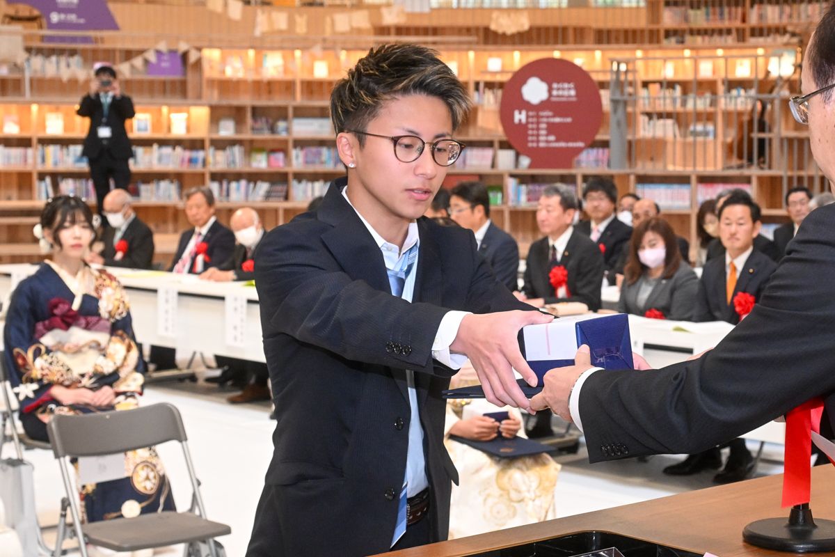 成人証書と記念品を受け取る出席者。