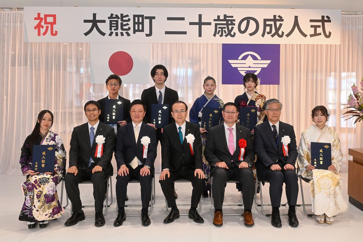 町の関係者との記念撮影に緊張した表情を見せる出席者たち。