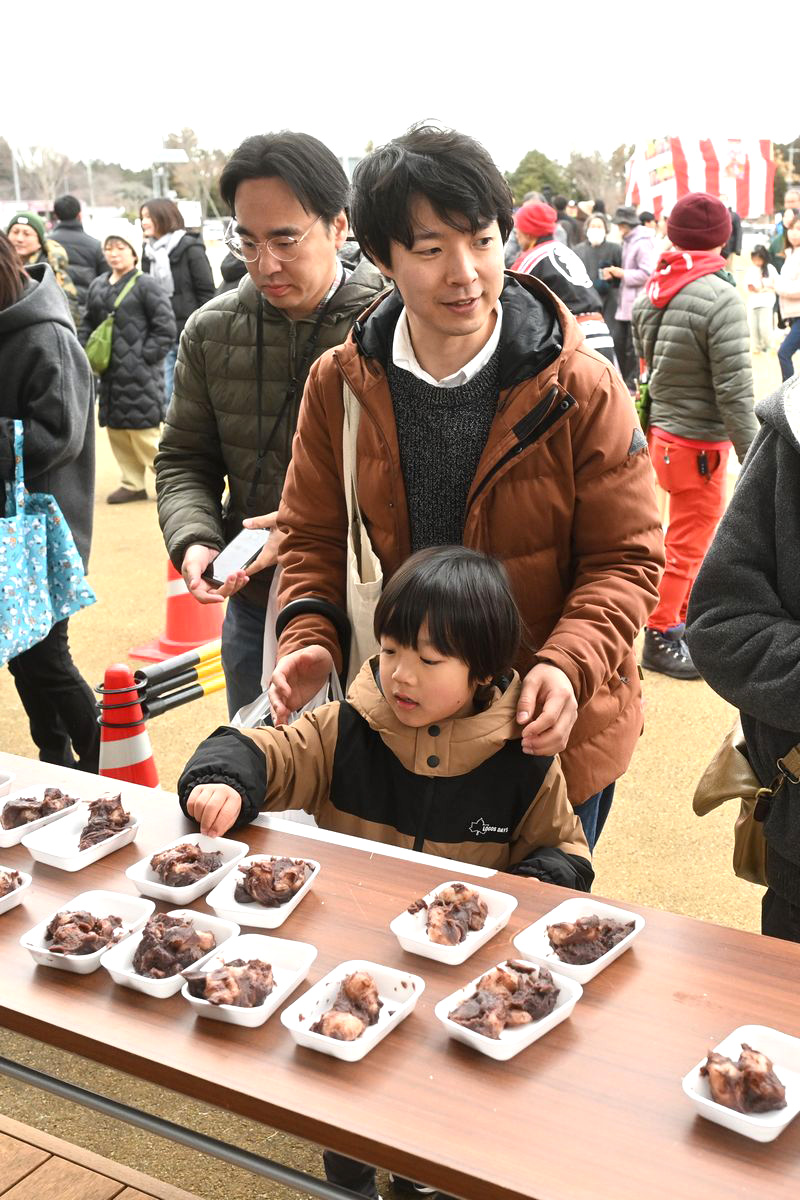 あんこ餅がたくさん並べられた机から、自分の分を選ぶ子ども。