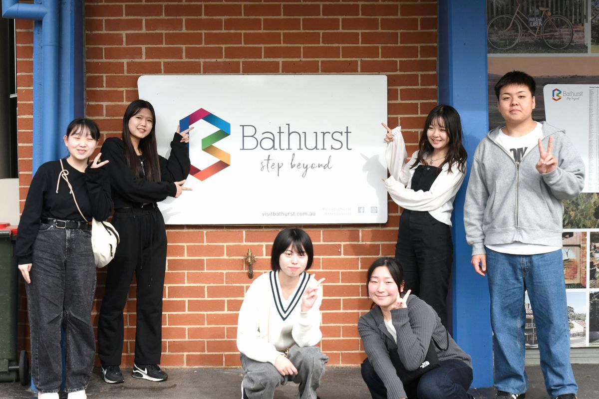 Bathurst step beyondと記された看板の前で記念撮影をする派遣団の団員ら