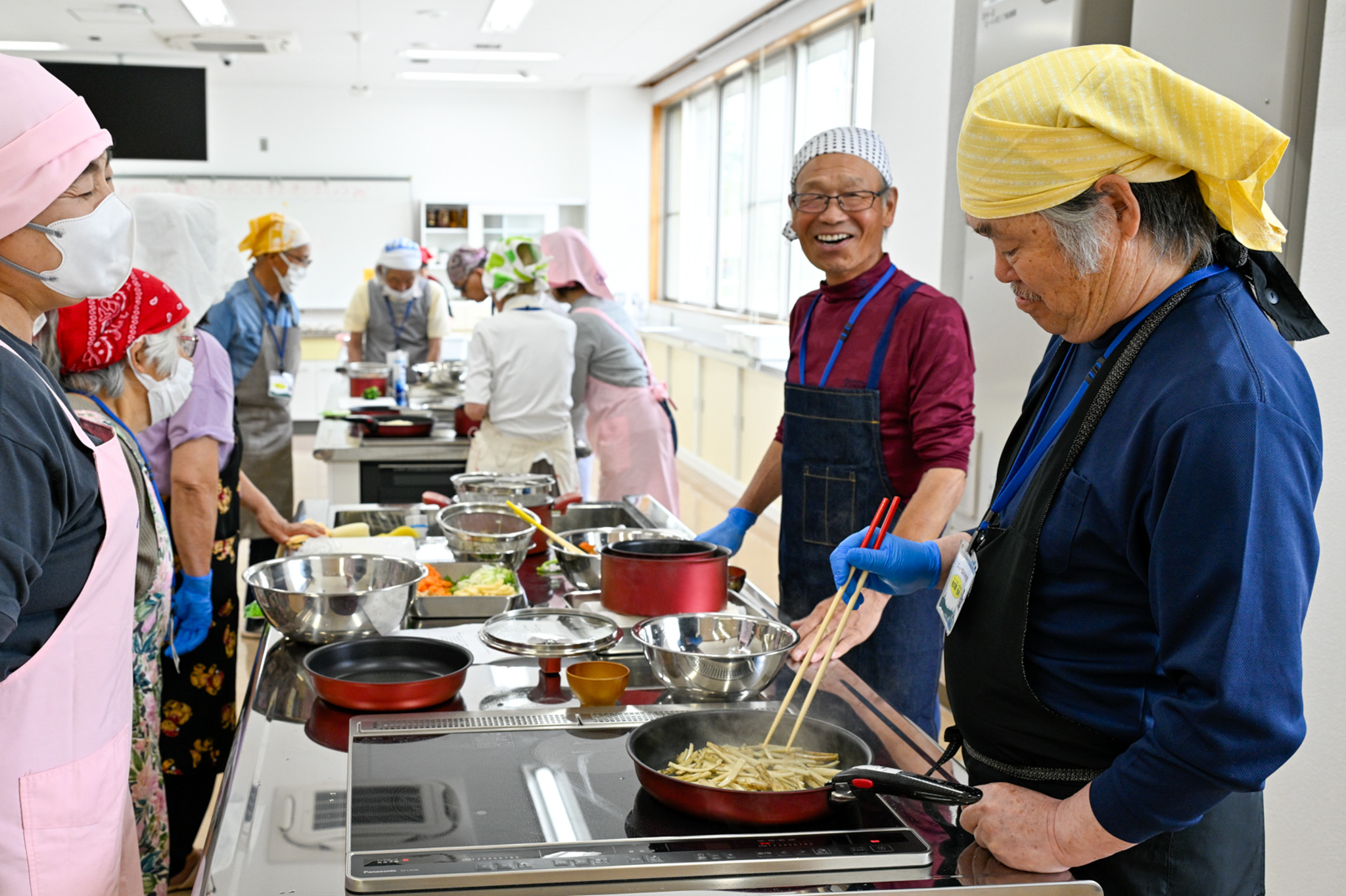 笑顔あふれる中、ごぼうを炒める参加者