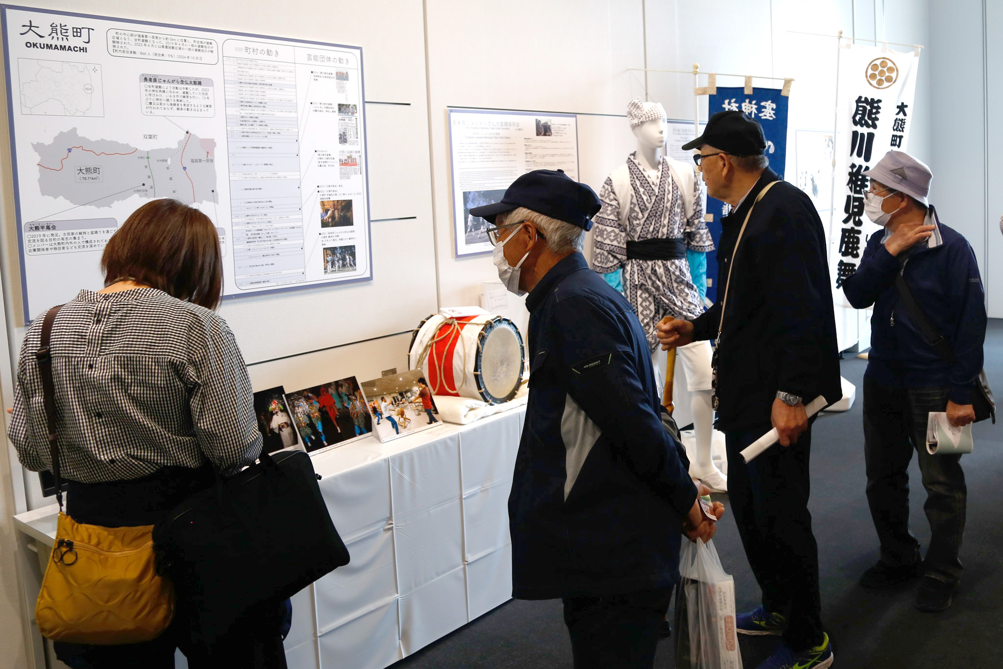 真剣なまなざしで展示を見つめ、町の記憶に触れる参加者ら