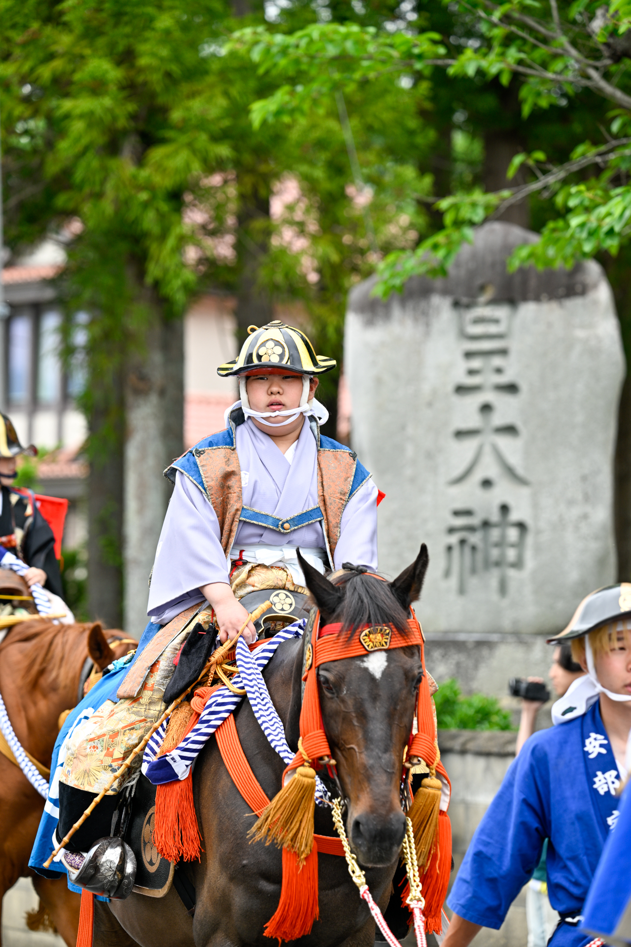 馬にまたがり、陣笠と羽織をまとって小高の町内を進む騎馬隊。