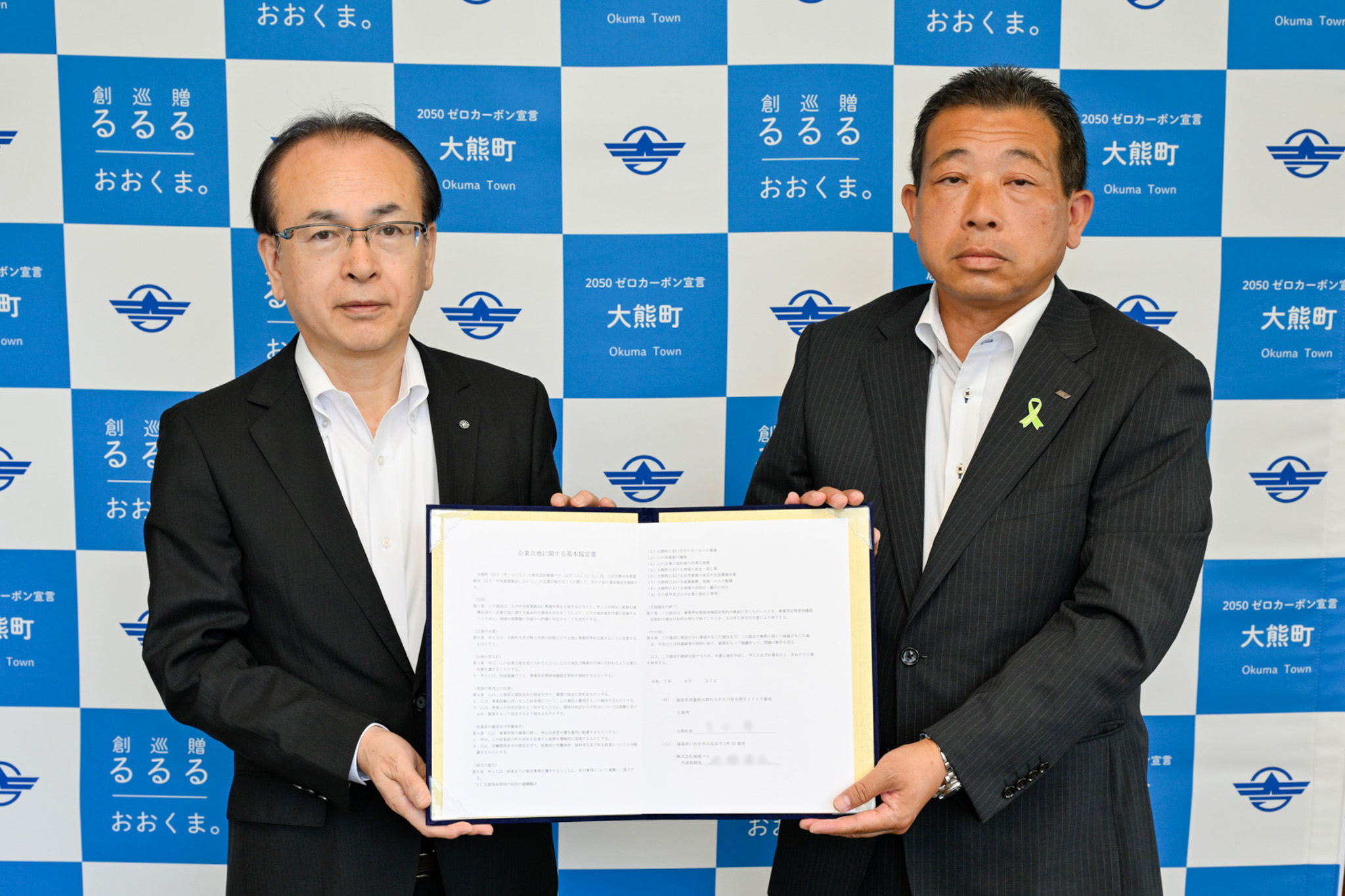 協定書を交わす佐藤社長（右）と吉田町長