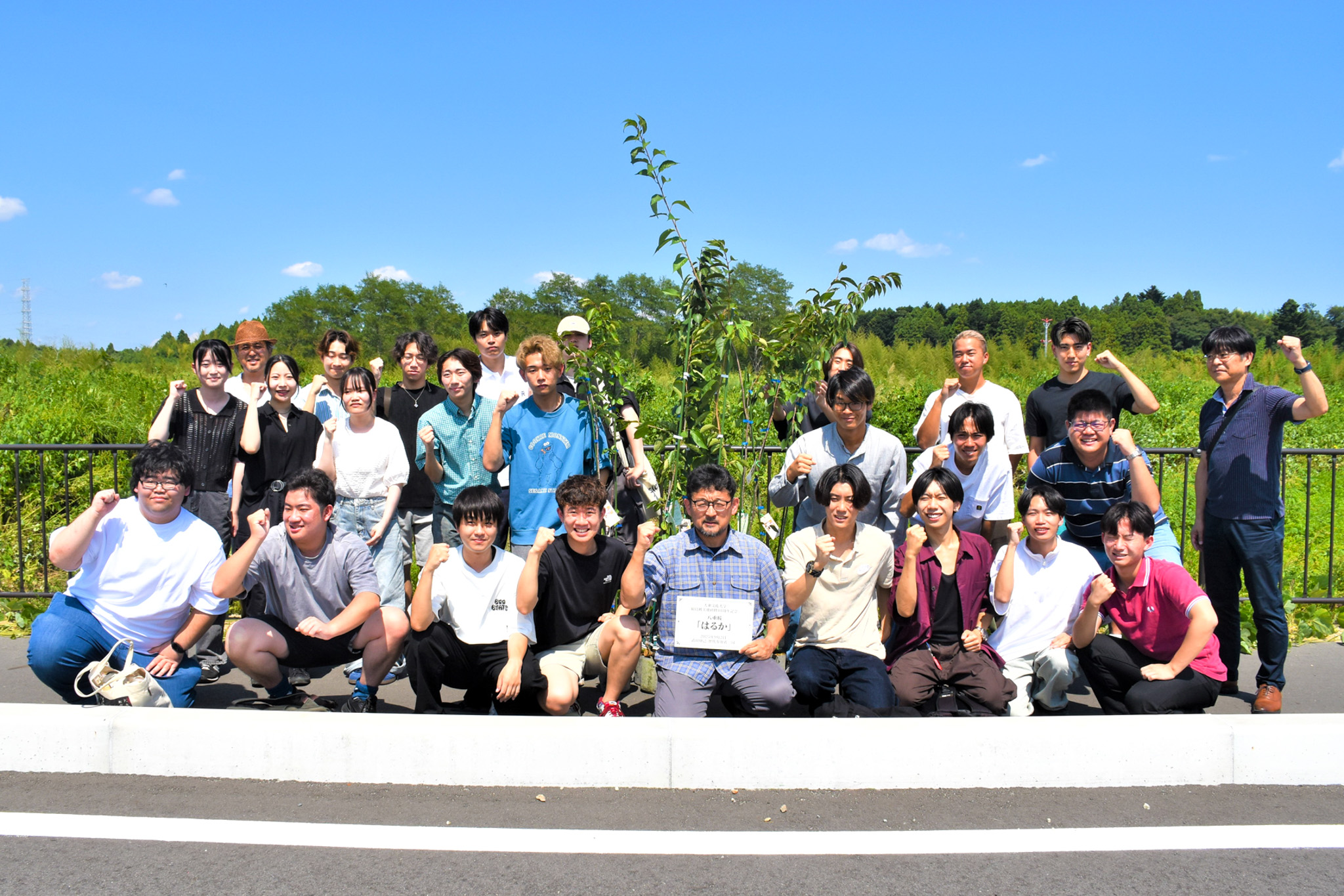 植樹した「はるか」の前で記念撮影に収まる学生ら（福島民友新聞社提供）
