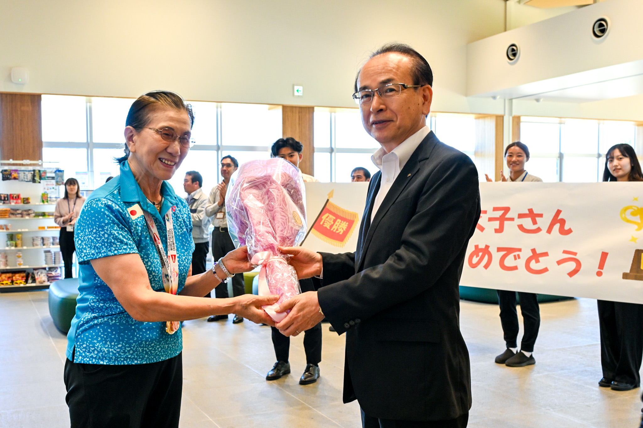 世界一の偉業を報告し、笑顔で迎えられる佐久間さん（左）