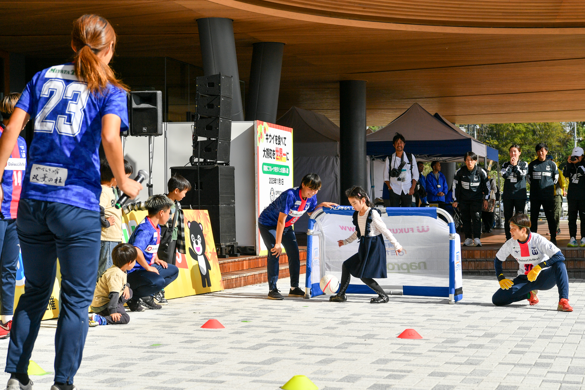 選手たちが見守る中、子どもがボールを蹴って障害物のあるコースに挑戦ししました。