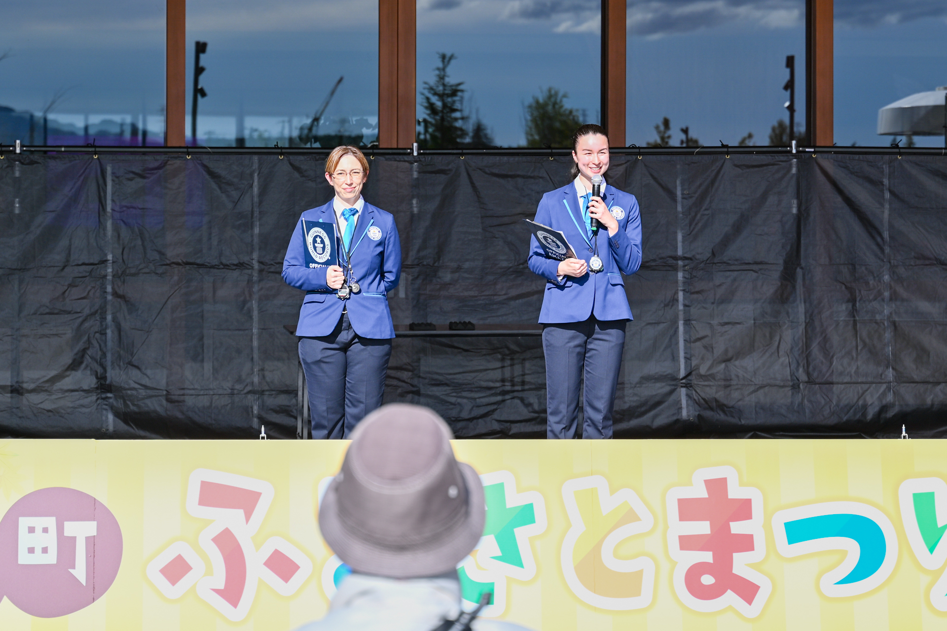 ステージ上に立つギネス公式認定員2人。挑戦の説明や配布物の確認が行われる中、参加者たちは興奮を抑えながら耳を傾けていました。