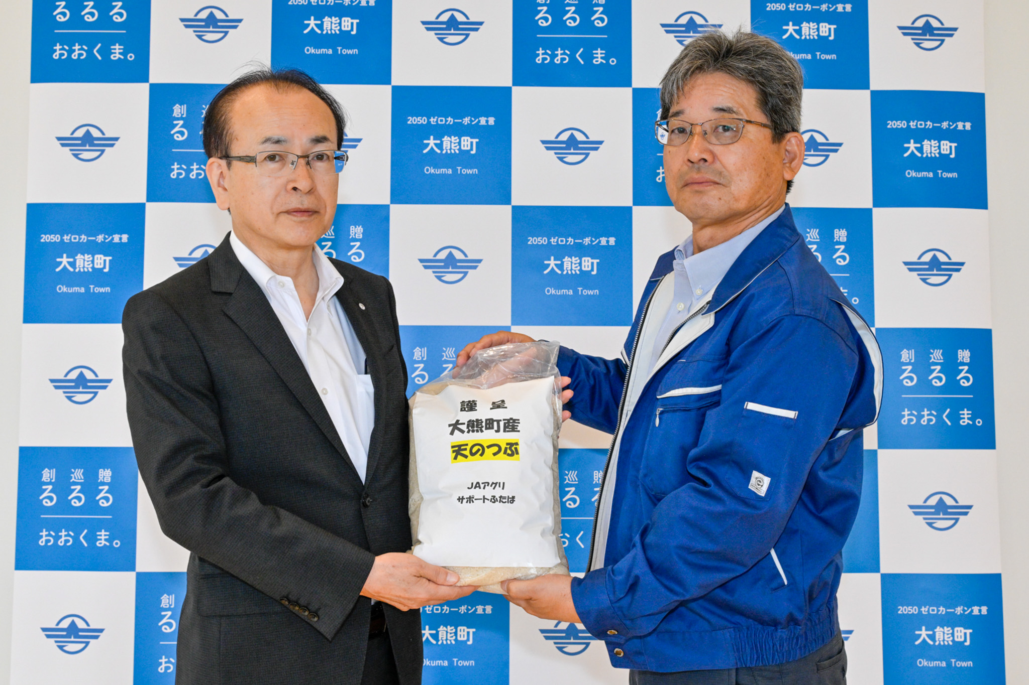 町内産天のつぶを手渡した榎本代表(右)