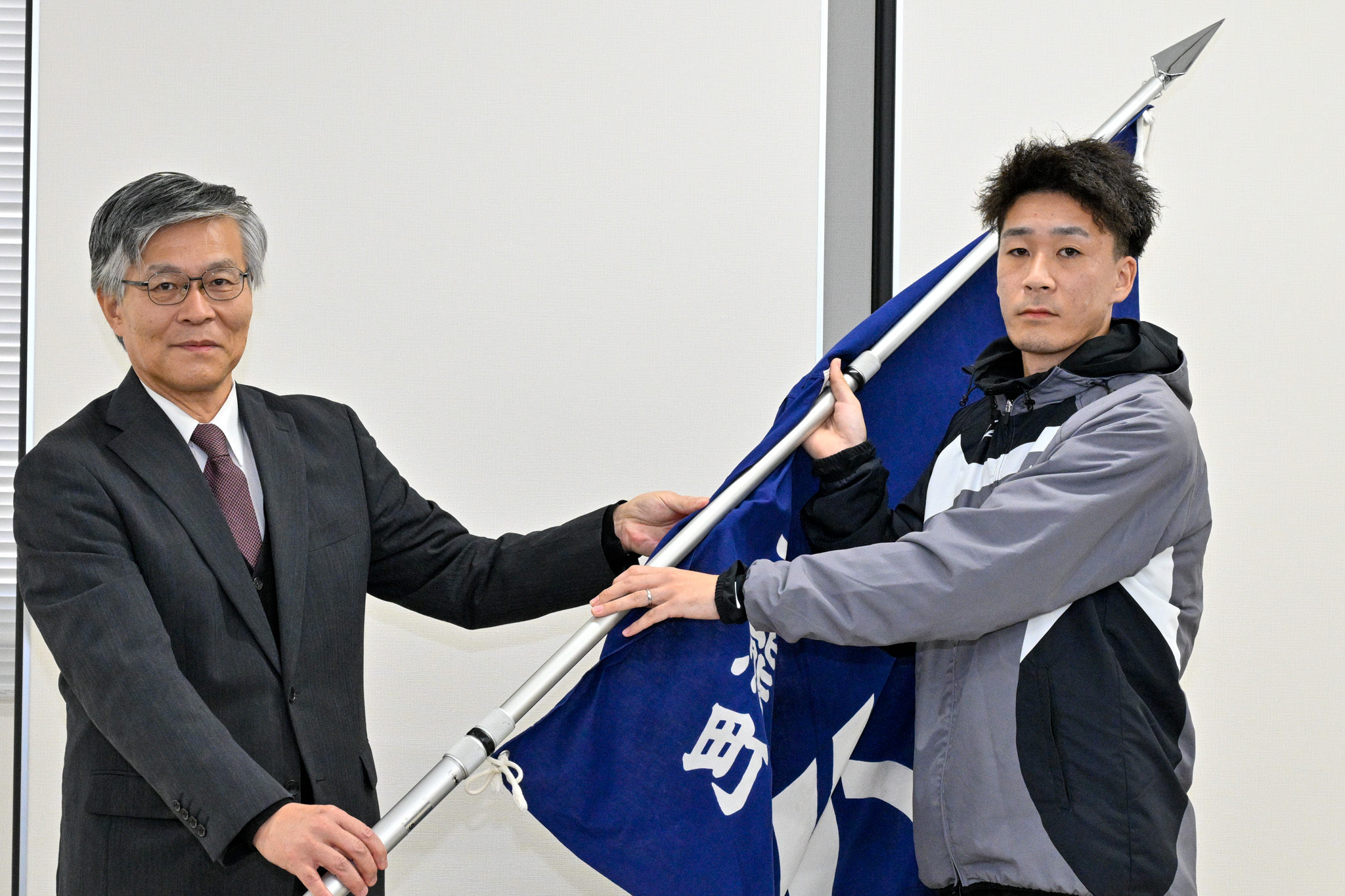 教育長から授与された町旗を、教育長と主将2人が共に手にしました。