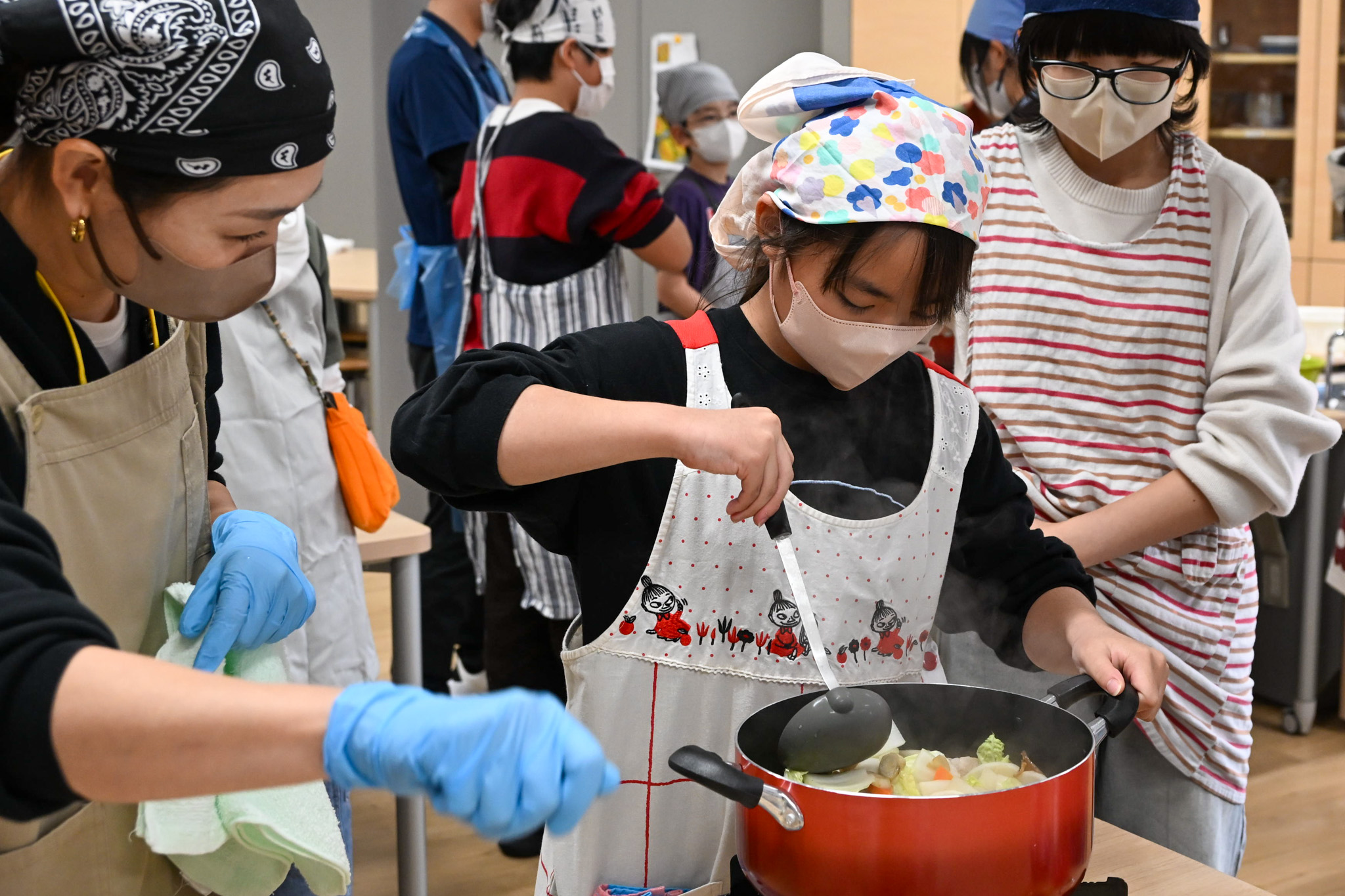 子どもたちの調理を、隣でじっと温かく見守るボランティアのまなざしが印象的です。