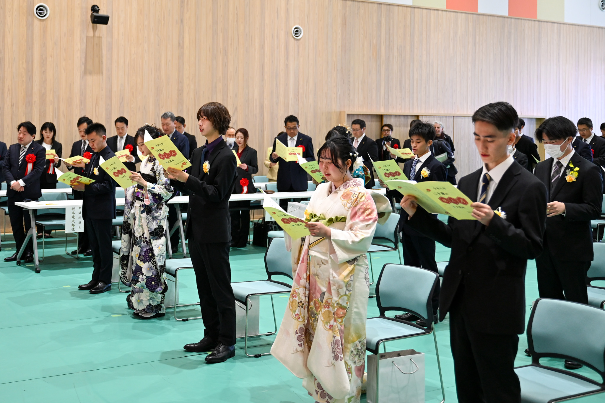 写真は、町民憲章を唱和する新成人と出席者の様子です。会場に集まった全員が起立し、式次第に記された町民憲章を読み上げました。