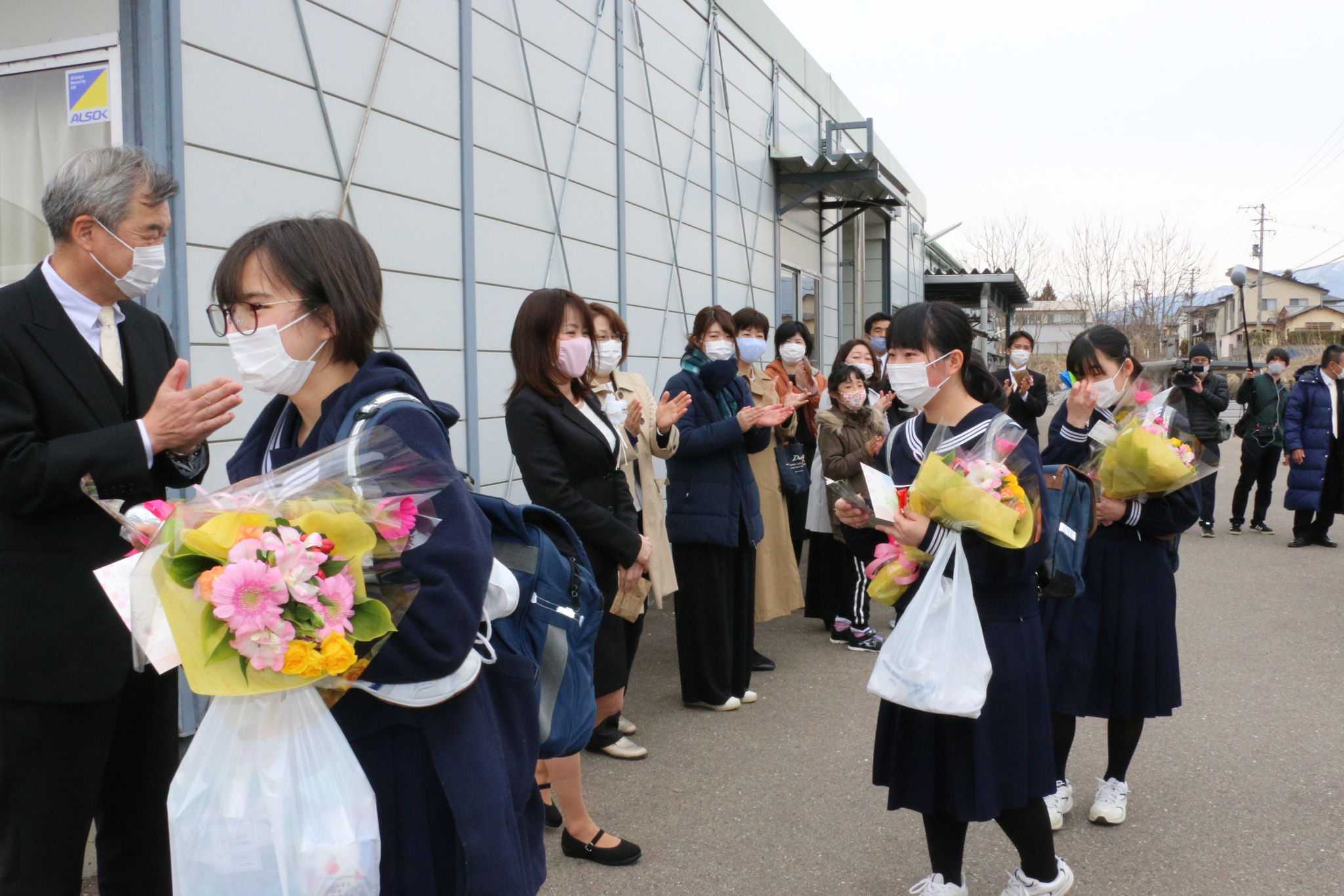 仮設校舎を巣立つ3人を、拍手で見送る在校生と地域の皆さん