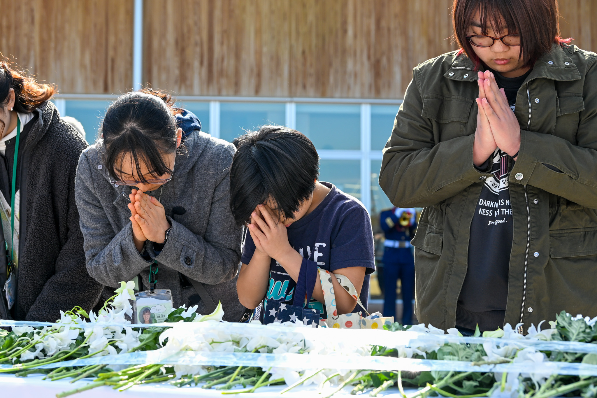 献花台に向かい、そっと手を合わせる参加者