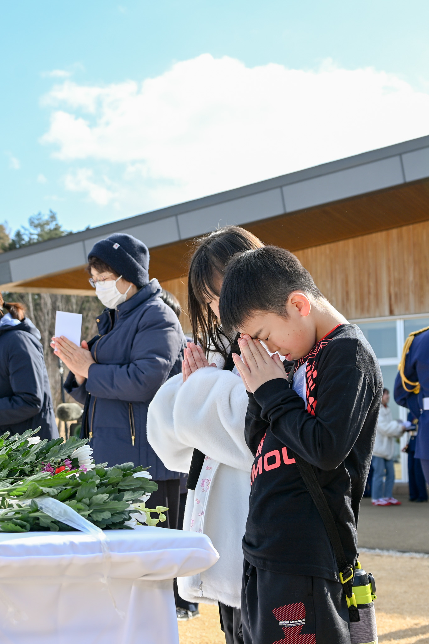 献花台に向かい、そっと手を合わせる参加者