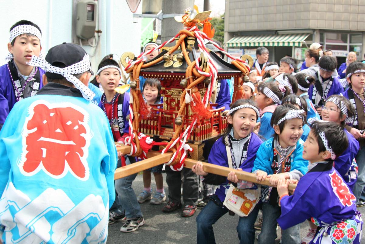 神輿を担ぎ、元気いっぱいの掛け声で町を練り歩く子どもたち