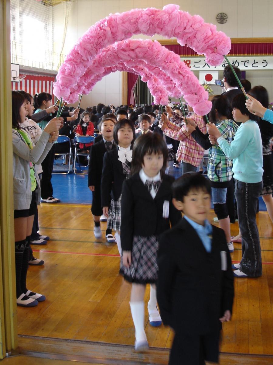 上級生が作る花のトンネルをくぐり退場する新入学児