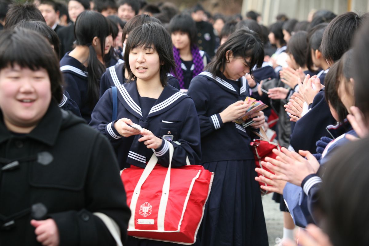 在校生のお見送りの列の中を感謝の笑顔で通る卒業生