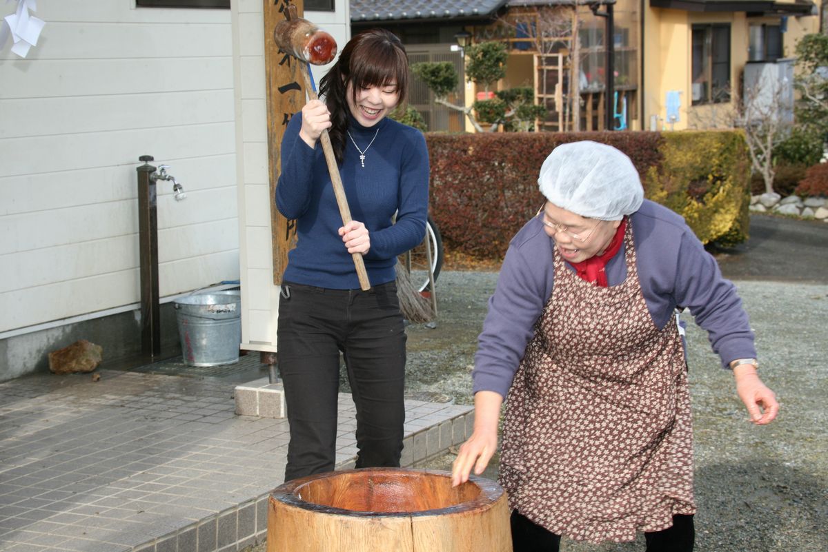 交流会会場の公民館前でもちつきをする町民たち