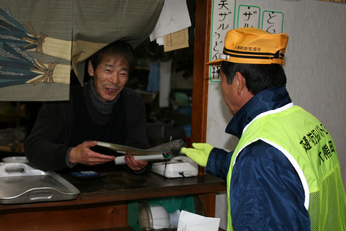 防犯協会員からチラシを受け取る飲食店の方