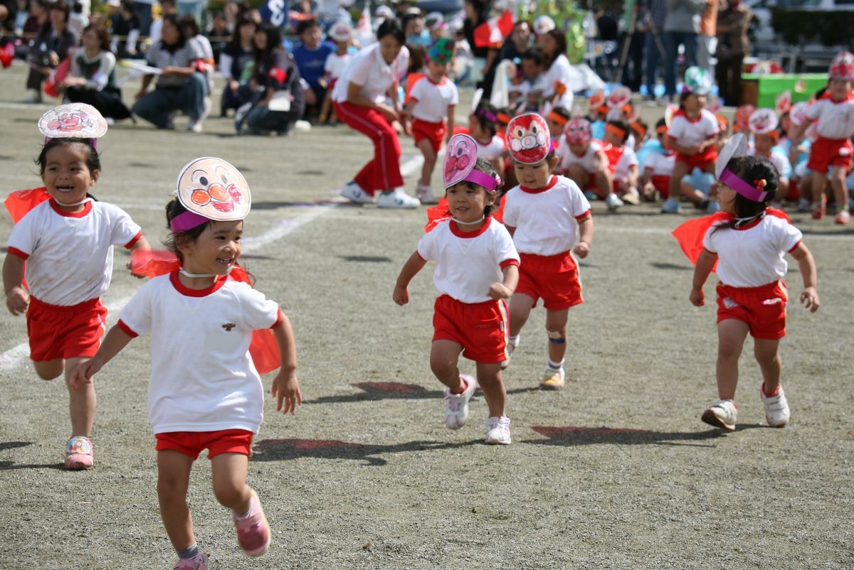 それぞれ色を塗ったアンパンマンの冠を付けゴールを目指して走る子どもたち