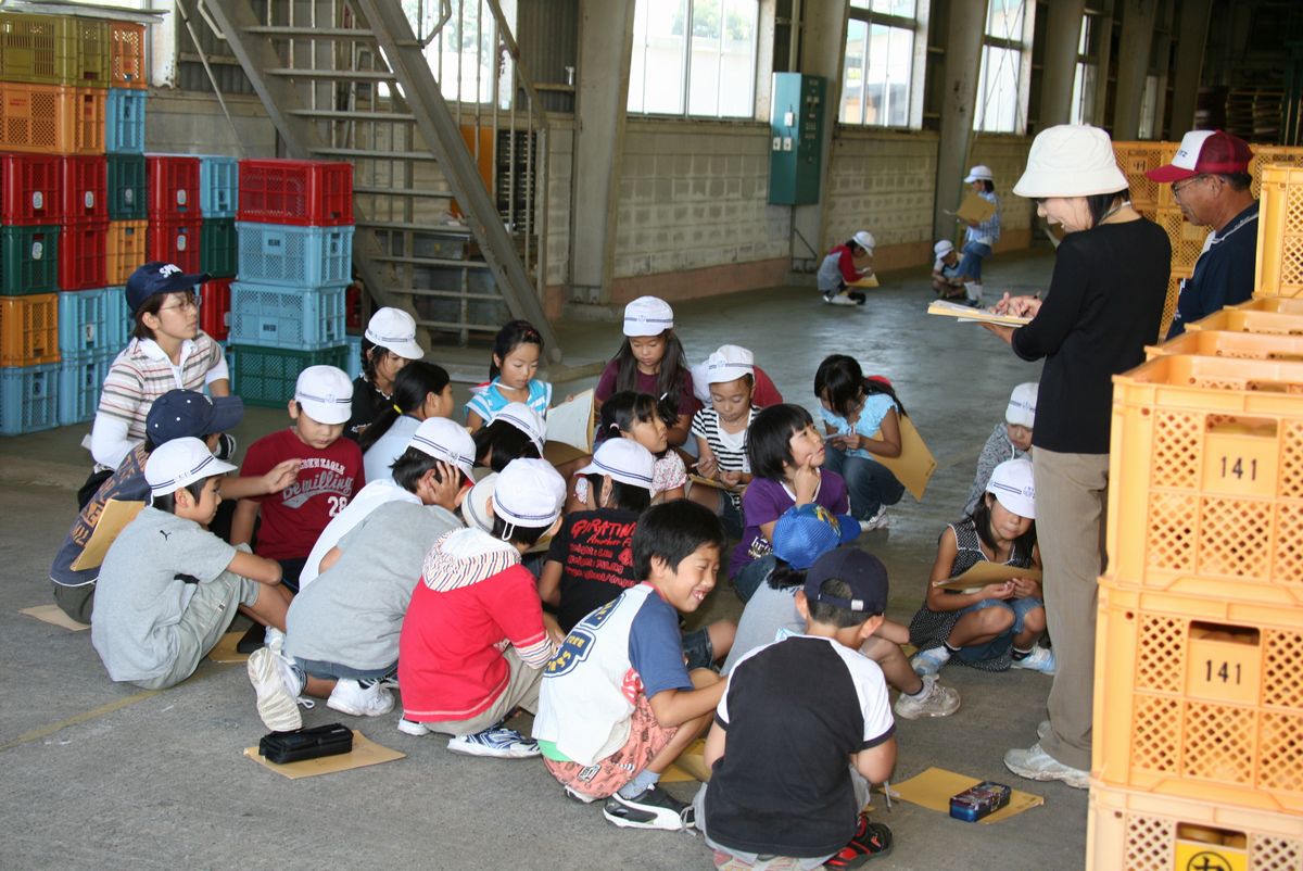 JAふたばの大熊果樹部会員から選果場での出荷までの工程の説明を受ける子どもたち