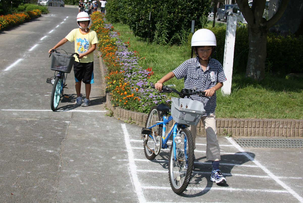 横断歩道の前で自転車を降り歩いて横断歩道を渡る児童