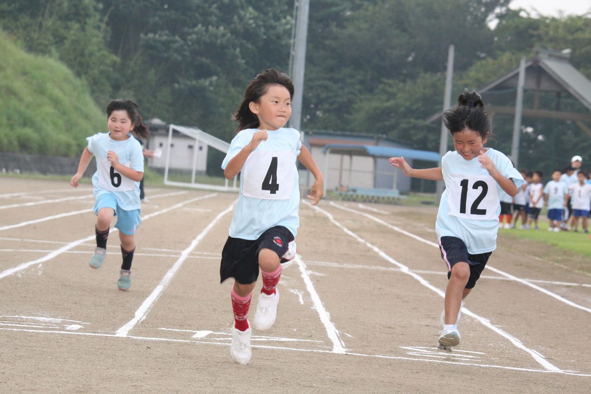 小学生低学年女子100メートル走、笑顔でゴール