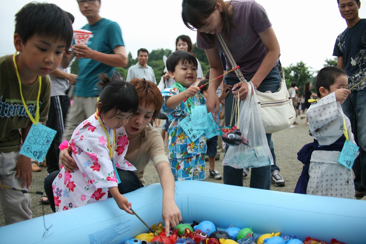 魚の形のビニール風船を竿で釣って楽しむ子どもたち