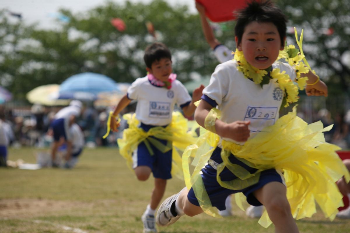 首にレイを下げ、フラガールの格好でゴールする2年生