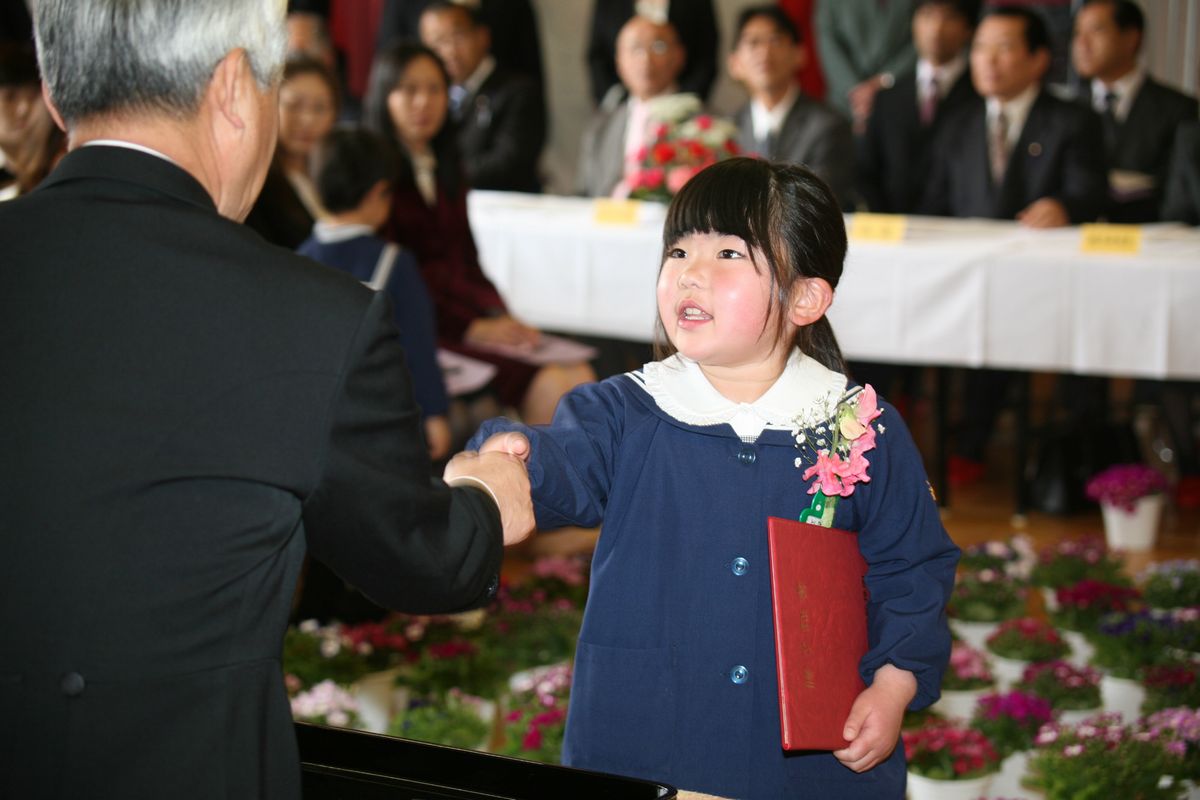 園長先生から終了証書を受け取り、握手を交わす卒園児