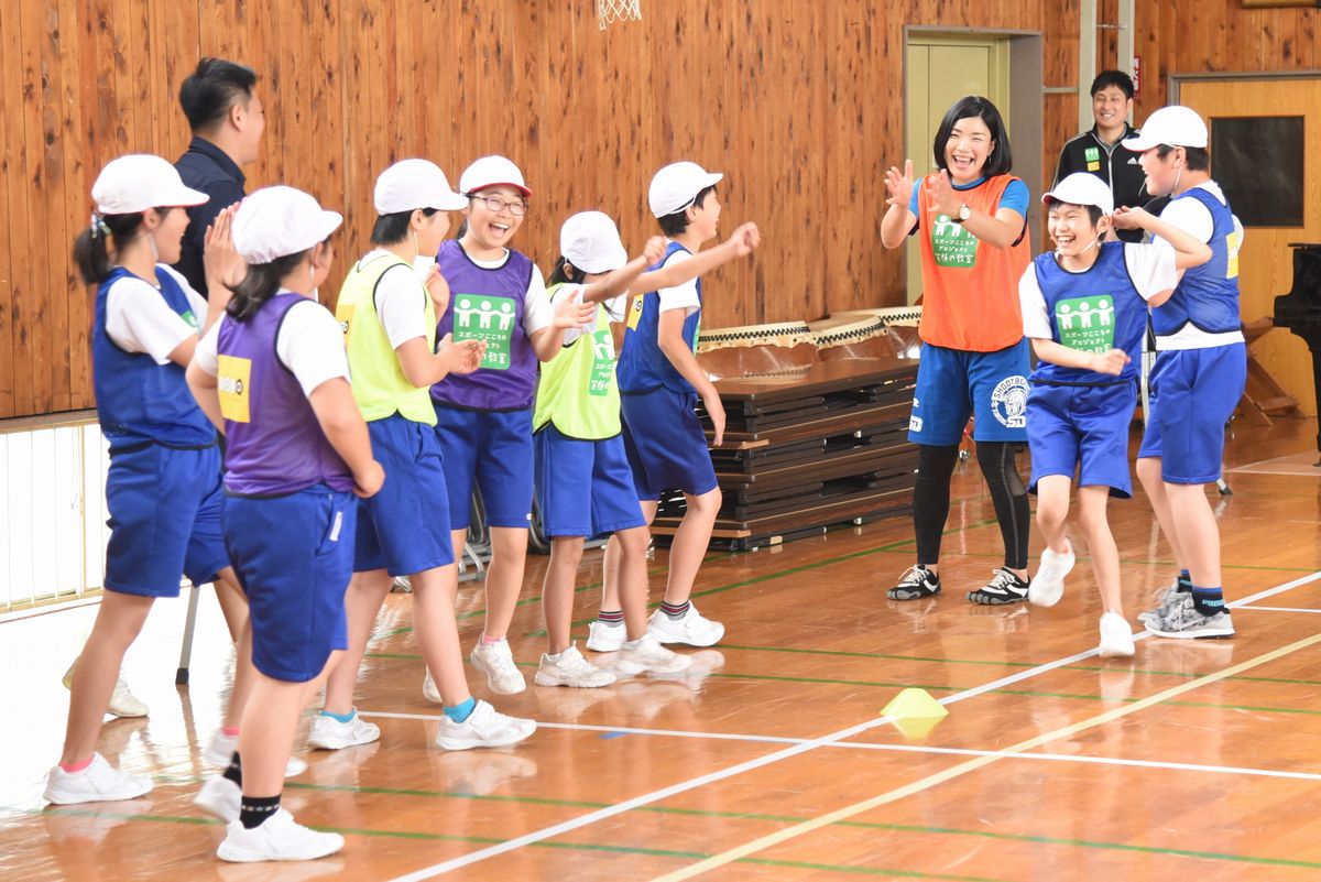 拍手と笑顔で喜び合う高橋さんと児童たち