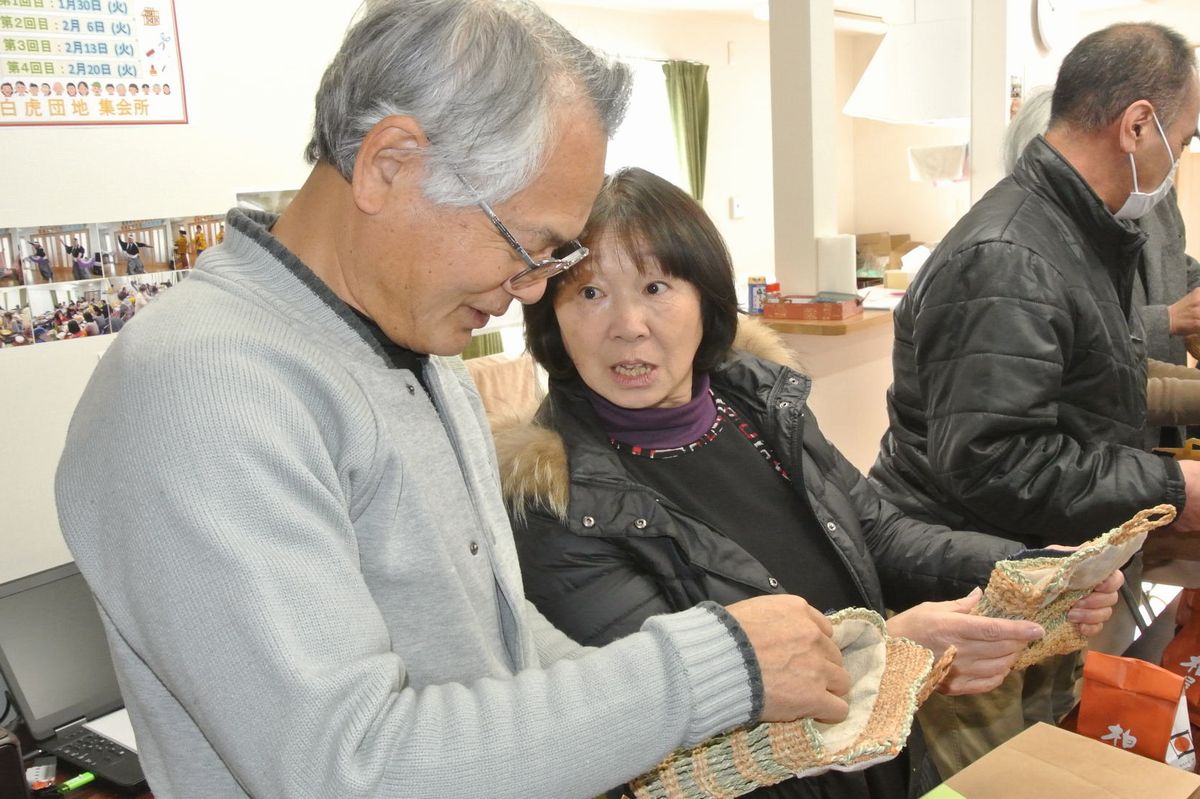 贈られたバッグを眺め、嬉しそうに話す町民