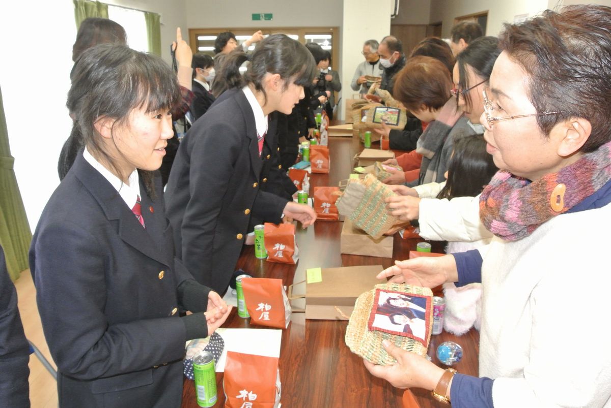 縫い付けられた絵画について会話が弾む生徒と町民